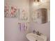 Charming powder room featuring floral decor, oval mirror, and a pedestal sink with modern faucet at 1343 Riverview Run Ln, Suwanee, GA 30024