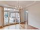 Bright dining room showcasing a modern chandelier, hardwood floors, and large windows with a neighborhood view at 1343 Riverview Run Ln, Suwanee, GA 30024