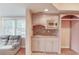 An elegant wet bar features granite countertops, tile backsplash, a microwave, and decorative lighting at 1343 Riverview Run Ln, Suwanee, GA 30024