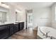 A bathroom with dual sinks, a soaking tub, and sleek dark wood-style floors at 156 Marchmont Dr, Locust Grove, GA 30248