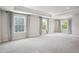 Airy bedroom features tray ceilings, neutral carpet, and lots of light streaming through several windows at 156 Marchmont Dr, Locust Grove, GA 30248
