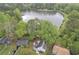 Beautiful aerial view of a quaint blue home next to a placid lake, surrounded by verdant trees and landscaping at 1077 Mainstreet Valley Dr, Stone Mountain, GA 30088