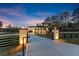 Long driveway leading up to a modern brick home, framed by a black fence and lighted entry pillars at 1688 Mineral Springs Rd, Hoschton, GA 30548