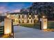 Stunning two-story home with a gated entrance and brick accents illuminated by stylish outdoor lighting at 1688 Mineral Springs Rd, Hoschton, GA 30548