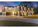 Stunning two-story home with a brick exterior, multiple car garage and an expansive driveway at twilight at 1688 Mineral Springs Rd, Hoschton, GA 30548
