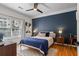 Cozy bedroom with wood floors, a navy accent wall, a ceiling fan, and large window with natural light at 1850 Cotillion Dr # 2221, Atlanta, GA 30338