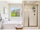 This bright bathroom features a soaking tub under a window and a separate shower with glass doors at 103 Cottage Way, Euharlee, GA 30145