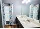 Bathroom featuring double vanity with dark cabinets, ample counter space, framed mirror, and floral-patterned curtains at 113 Citadel Dr, Hampton, GA 30228