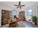 Well-lit home office with a large desk, wooden shelving, and a ceiling fan, offering a productive workspace at 570 Harris Sw Ct, Marietta, GA 30060