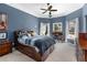Spacious bedroom with blue walls, a bed with storage, desk, ceiling fan, and natural light from two windows at 4020 Balleycastle Ln, Duluth, GA 30097