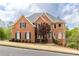 Elegant two-story brick home featuring a manicured lawn and a classic design with blue shutters and a turret at 4020 Balleycastle Ln, Duluth, GA 30097