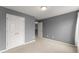 A carpeted bedroom with a large closet, gray walls, and an open door creates a simple but elegant space at 5950 Bridge Stone Ct, Cumming, GA 30028