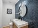 Stylish powder room with herringbone tile accent wall, round mirror, and modern fixtures at 6124 Kings Mountain Ct, Stone Mountain, GA 30087