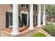Inviting front porch of a brick home featuring elegant columns, black shutters, and stylish decorative accents at 6124 Kings Mountain Ct, Stone Mountain, GA 30087