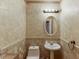 Tastefully decorated half bathroom with a pedestal sink, decorative mirror, and wainscotting at 1480 Bramlett Forest Se Trl, Lawrenceville, GA 30045