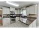 A view of the kitchen with stainless steel appliances, a dark granite countertop, and white cabinetry at 1480 Bramlett Forest Se Trl, Lawrenceville, GA 30045