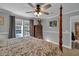 Well-lit bedroom with four-poster bed, ceiling fan, and view of the outside at 2466 Monroe Jersey Rd, Covington, GA 30014