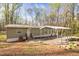 Quaint single-story home with covered parking nestled in a wooded setting with a lawn at 2466 Monroe Jersey Rd, Covington, GA 30014