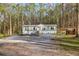 Single-story home with white trim, surrounded by a wooded lot and a gravel driveway at 2466 Monroe Jersey Rd, Covington, GA 30014