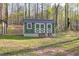 Wooden shed with double doors and decorative lattice trim set against a wooded backdrop at 2466 Monroe Jersey Rd, Covington, GA 30014