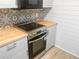 Kitchen featuring stainless steel appliances, bright wooden countertops, and patterned tile backsplash at 475 Mount Vernon Ne Hwy # 226C, Atlanta, GA 30328