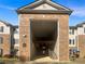 Apartment building entrance featuring brick facade, stairs, and multiple levels under a blue sky at 7302 Par Four Way, Lithonia, GA 30038