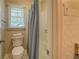A traditional bathroom showing a toilet, a window, and a tub shower with a blue curtain at 1283 Maple St, Conyers, GA 30013