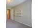 A bright bedroom with an open doorway, three shelves on the wall, and neutral carpet at 1283 Maple St, Conyers, GA 30013