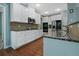 Well-lit kitchen boasts granite counters, stainless appliances, white cabinetry and hardwood floors at 1610 Apollo Dr, Suwanee, GA 30024