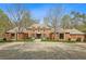 Expansive front exterior featuring a stately brick home with ample parking and mature trees at 4195 Woodland Brook Se Dr, Atlanta, GA 30339