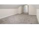 Finished attic space with neutral paint, carpeting and door to another room at 6493 Crooked Creek Pl, Lithonia, GA 30058