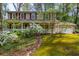 Charming two-story home with red shutters, a white porch, and a manicured lawn with flowering bushes at 6795 Brandon Mill Rd, Atlanta, GA 30328
