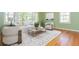 Sunlit living room featuring hardwood floors, a comfortable sofa, chairs, and a patterned area rug at 6795 Brandon Mill Rd, Atlanta, GA 30328