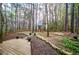 Wooded backyard featuring a charming stone pathway and spacious wooden deck for relaxation at 9176 Lakeview Parkway, Villa Rica, GA 30180