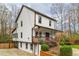 Side view of the white two-story home featuring a covered porch and walkout basement at 3991 Centennial Trl, Duluth, GA 30096