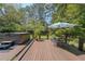 Relaxing deck area featuring a hot tub, table with chairs, and umbrella, surrounded by lush greenery at 3530 Embry Cir, Atlanta, GA 30341