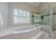 Bright bathroom featuring a soaking tub, shower, and natural light from the window at 370 Royal Birkdale Ct, Johns Creek, GA 30097