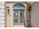 Close up of the front door with decorative glass flanked by sconces, stone and stucco at 370 Royal Birkdale Ct, Johns Creek, GA 30097