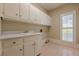Laundry room features lots of cabinets, pink tile floor, and a window with natural light at 370 Royal Birkdale Ct, Johns Creek, GA 30097