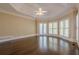 Light-filled main bedroom with tray ceiling, fan, hardwood floors, and shuttered windows and doors at 370 Royal Birkdale Ct, Johns Creek, GA 30097