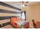 Bedroom with striped accent wall, ceiling fan, carpet and window with dark curtains at 5036 Maplecliff Dr, Sugar Hill, GA 30518