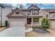 Charming two-story home featuring a covered front porch, two-car garage, and manicured landscaping at 5036 Maplecliff Dr, Sugar Hill, GA 30518