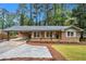 Charming brick home featuring a carport and inviting front porch in a lush, green setting at 2695 Peeler Rd, Dunwoody, GA 30360