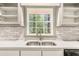 Close-up of kitchen sink with subway tile backsplash and view of trees at 2695 Peeler Rd, Dunwoody, GA 30360