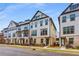 Row of craftsman townhomes featuring neutral colors, brick accents, and well-maintained landscaping under a blue sky at 3980 Allegretto Cir, Atlanta, GA 30339
