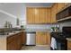 Galley kitchen featuring stainless steel dishwasher, wood cabinets, granite countertops, and black gas range at 1754 Heights Nw Cir # 11, Kennesaw, GA 30152
