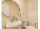 Powder room featuring a pedestal sink, round mirror, and neutral walls at 5130 N Peachtree Rd, Dunwoody, GA 30338