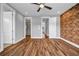 Bedroom with exposed brick wall, wood floor, ceiling fan, and doors to closet and other rooms at 267 Castleberry Station Sw Dr, Atlanta, GA 30313