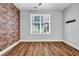 Cozy bedroom featuring a brick accent wall, hardwood floors, and a bright window, creating a warm and inviting space at 267 Castleberry Station Sw Dr, Atlanta, GA 30313