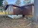 Exterior shot of the home showing the backyard, brown siding, and white painted cinder block foundation at 144 Flat Rock Rd, Oxford, GA 30054